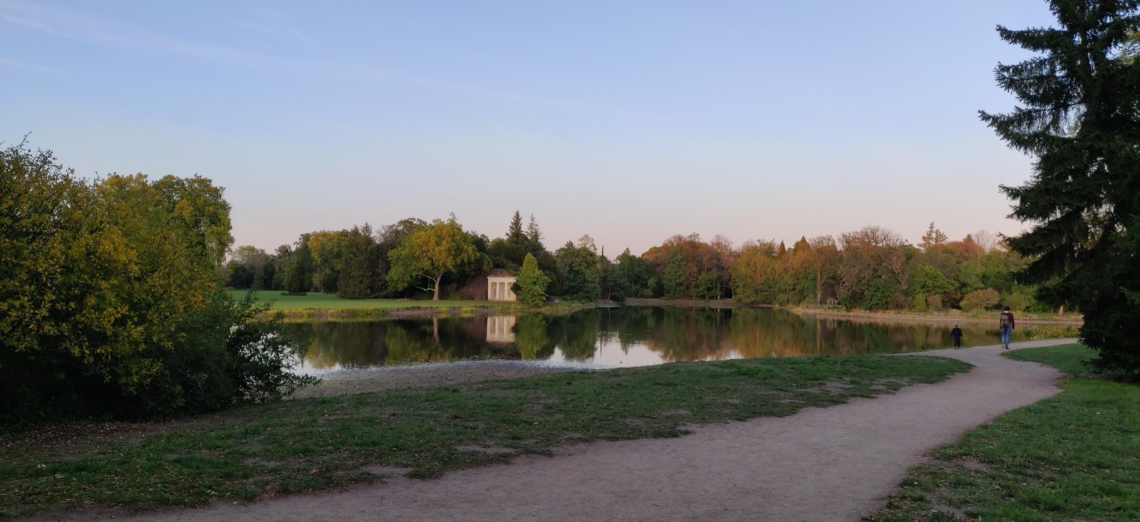 Englischer Park mit kleinem Wassertempel am Seeufer im Abendlicht